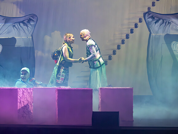 Teen und Ghost stehen sich gegenüber und halten Hände. Parent sitzt vorne auf einem Würfel, Nebel und Kissen im Hintergrund.-85163e